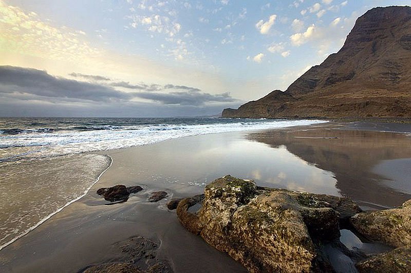 Playa del Risco in Agaete, Gran Canaria, with black sand, rocks and mountain cliffs